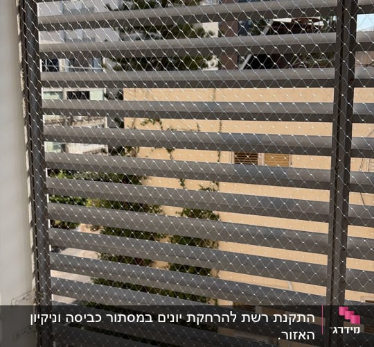 רשת מתכת על חלון עם נוף חיצוני